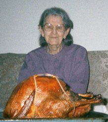 A picture of a smiling Mama Leary with a browned turkey on a tray in front of her.
