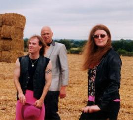 A picture of the band in a wheat feild after harvest with the wheat in bales in the left background.